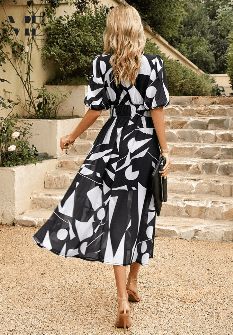 Black and white patterned midi dress with puff sleeves and gathered waist, shown from back