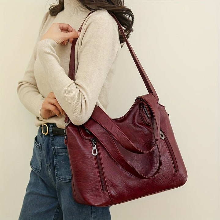 Lumi women’s tote bag in burgundy worn on shoulder with top zip and crossbody strap