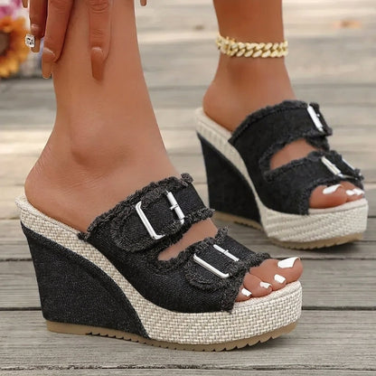 Black wedge sandals with two buckle straps, open toe, and textured espadrille sole