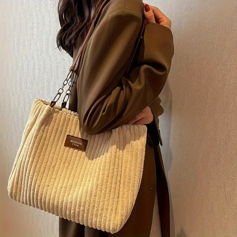 Corduroy tote bag in light tan carried with a long strap and short chain handle