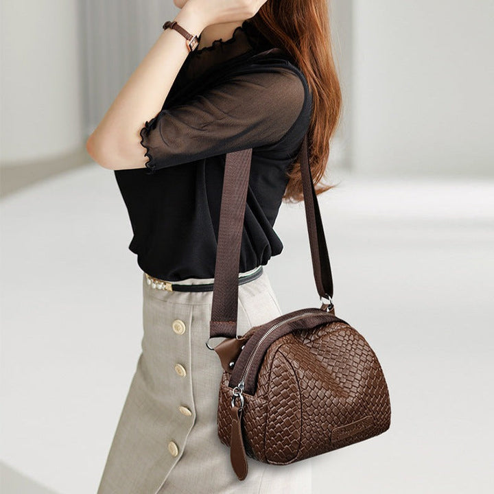 Brown woven-texture crossbody bag with zip top and shoulder strap, side view