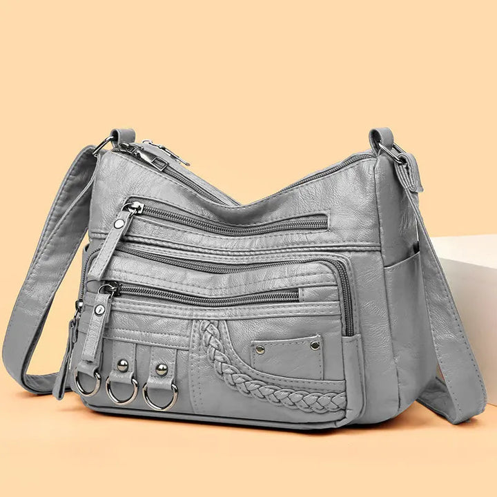 Grey multi-layer crossbody bag with zip pockets, braided front panel, and four ring key straps