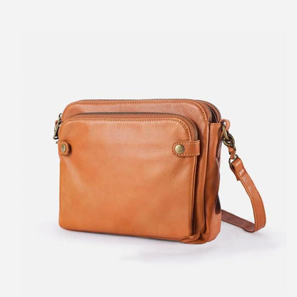 Orange-brown sleek crossbody bag with zip top, front pockets, and adjustable shoulder strap