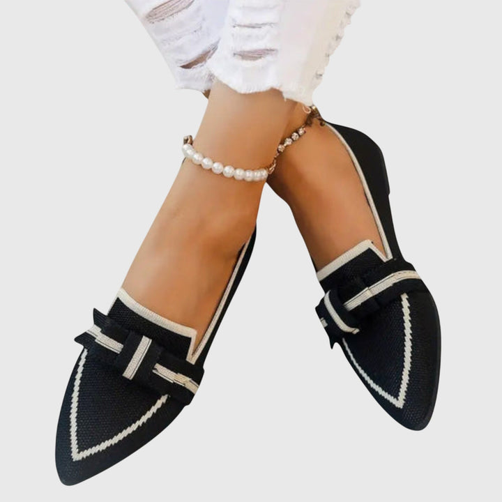 Black slip-on comfy shoes with white trim and side bow detail