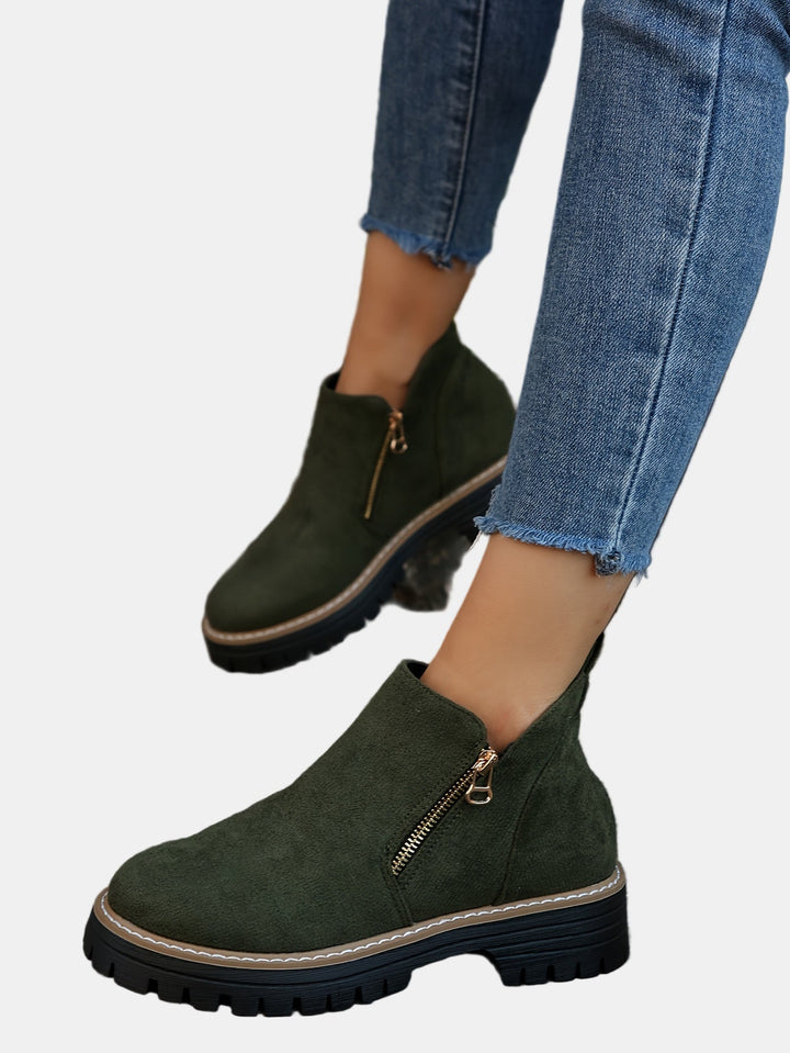 Green suede ankle boots with side zipper, tan stitching, and black treaded sole.