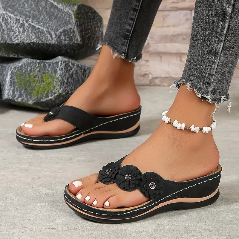 Black orthopedic sandals with floral applique, contrast stitching, and cushioned sole