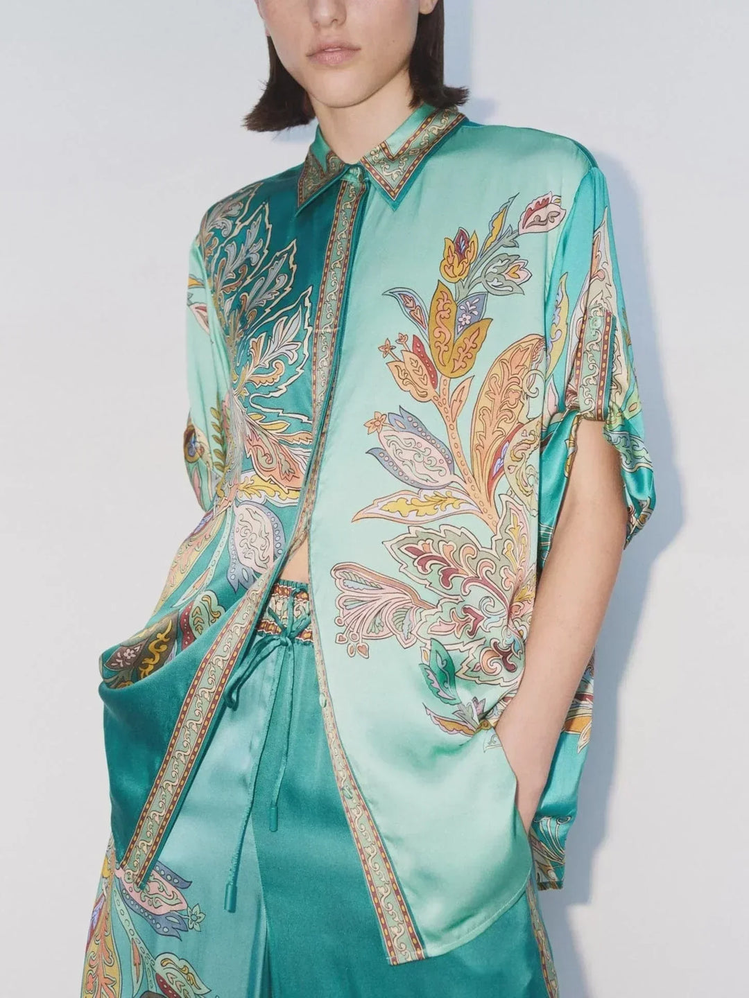 Turquoise paisley shirt with pointed collar, button placket, and cuff details