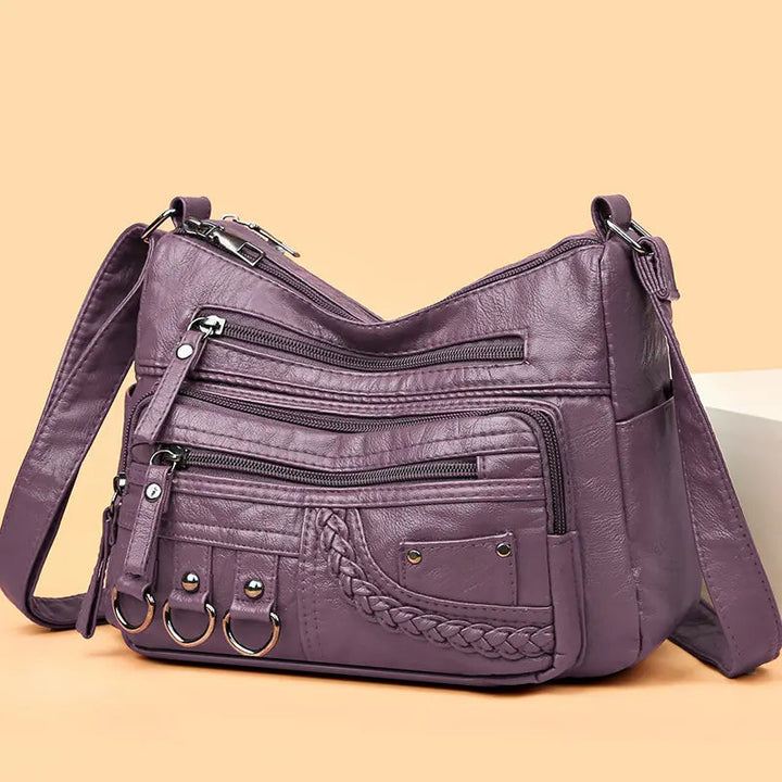 Purple multi-layer crossbody bag with zip compartments and braided front pocket detail