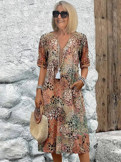 Mid-length V-neck dress in sandy beige with multicolor speckled pattern and tassel trim