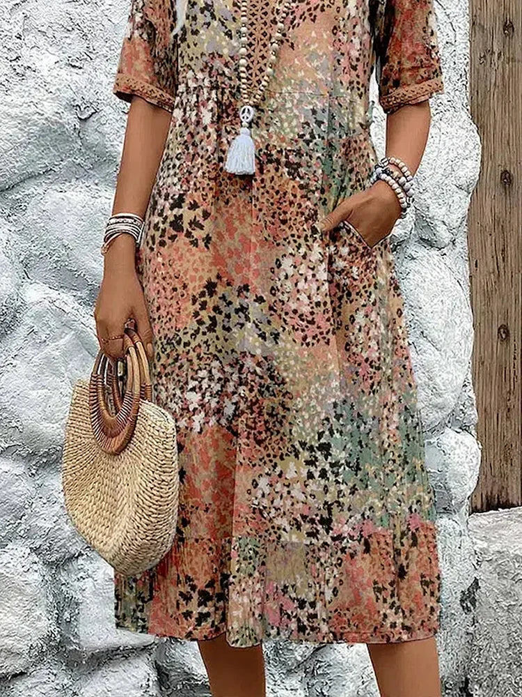 Mid-length V-neck dress hem in sandy beige with multicolor speckled pattern and tassel trim