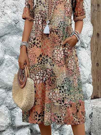 Mid-length V-neck dress hem in sandy beige with multicolor speckled pattern and tassel trim