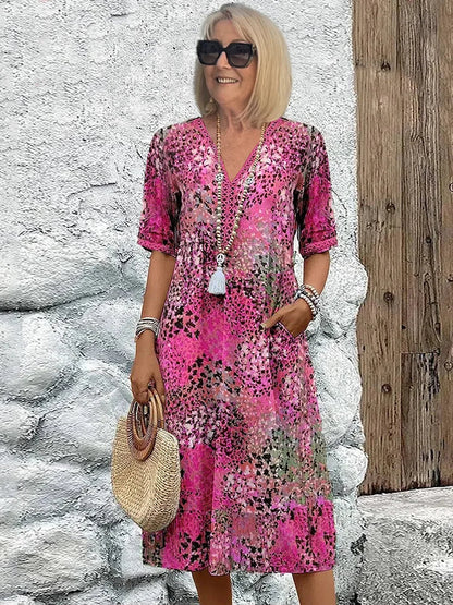 Mid-length V-neck dress in blush pink with multicolor speckled pattern and tassel trim