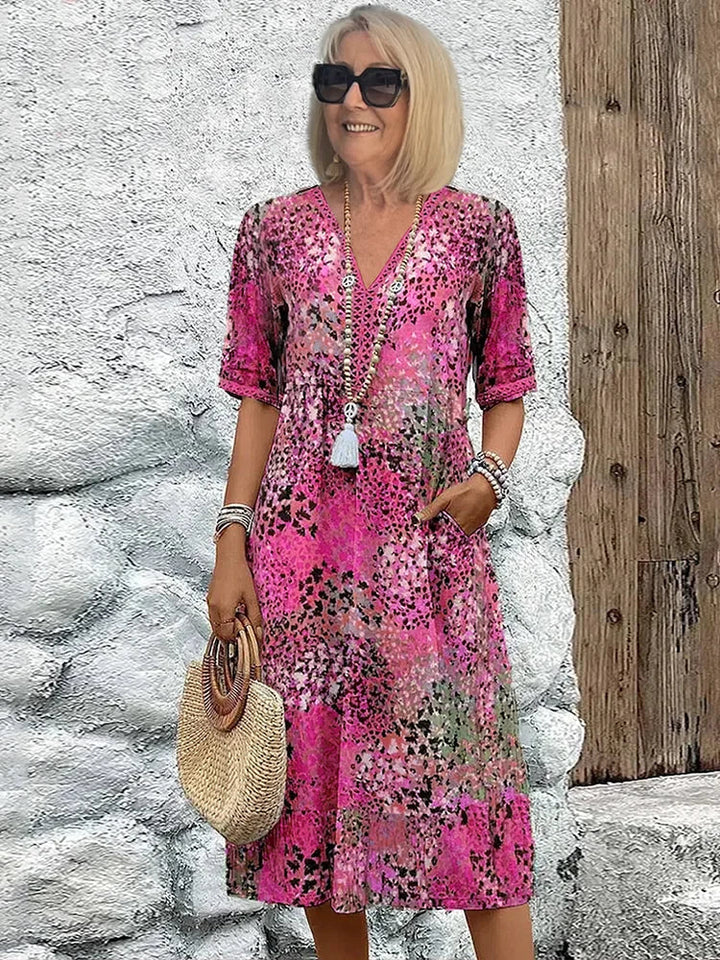 Mid-length V-neck dress in blush pink with multicolor speckled pattern and tassel trim