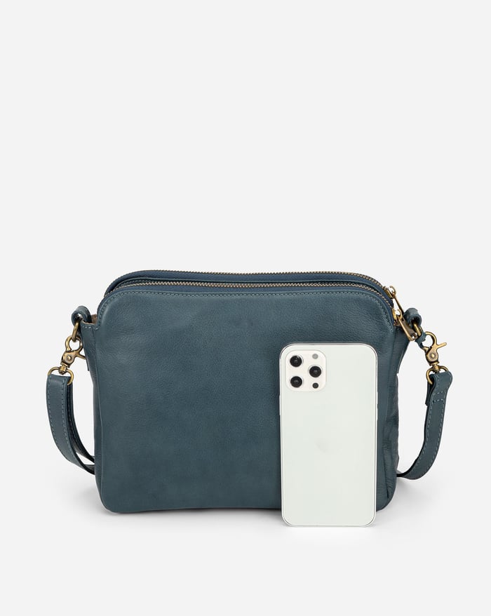 Jovie sleek three-layer crossbody bag in dark teal with phone tucked in front compartment