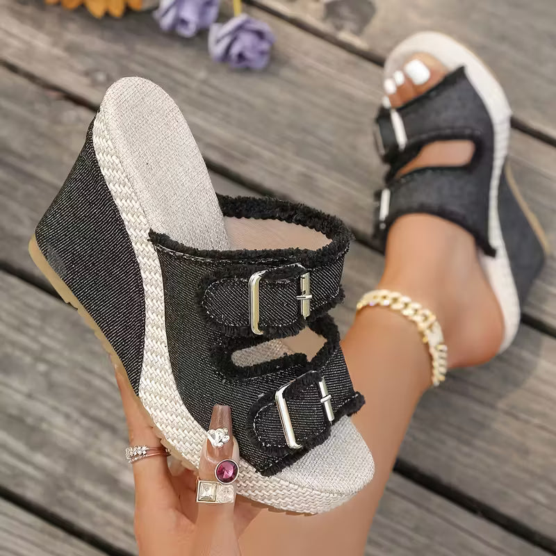 Black wedge sandals with frayed straps, two metal buckle accents, and open toe