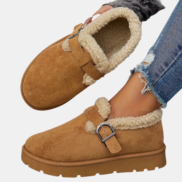 Brown fleece-lined ankle boot with shearling trim, buckled strap, thick tread sole