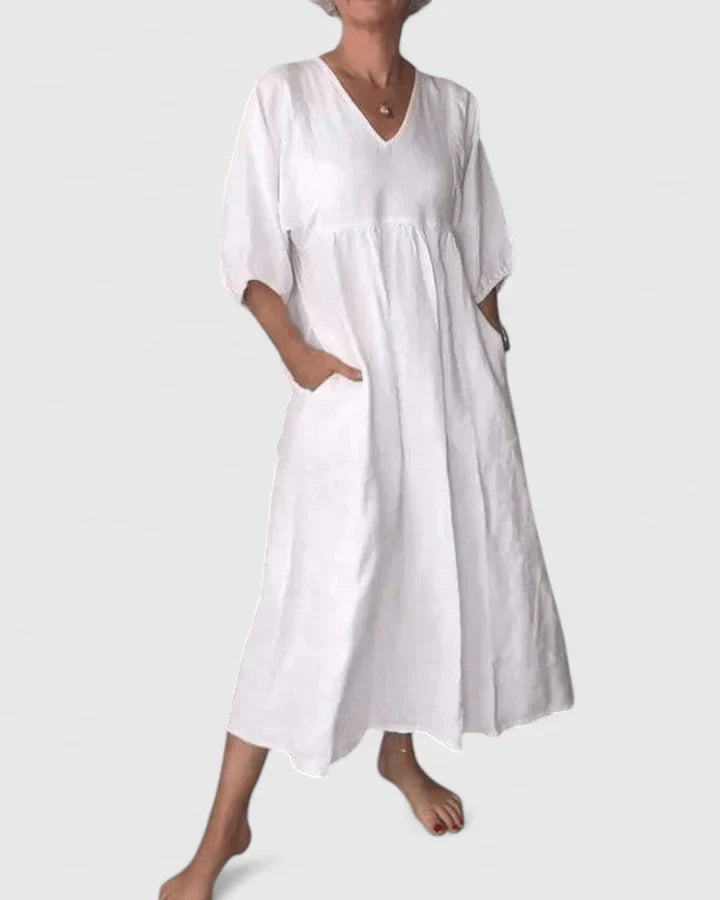 White maxi dress with V-neck, three-quarter sleeves, and gathered waist seam