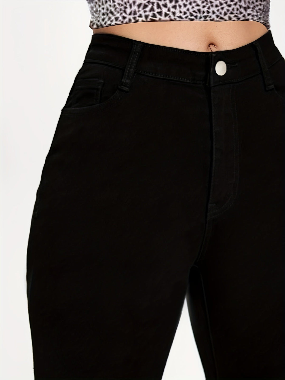 Black high-waist skinny jeans close-up of waistband button, belt loops and front seam
