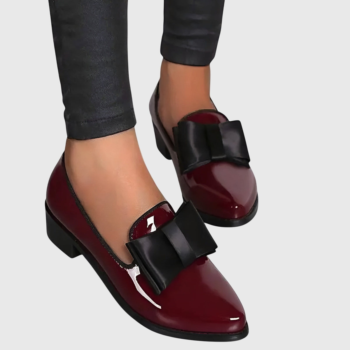 Burgundy patent loafer close-up with black strap across the top and rounded toe