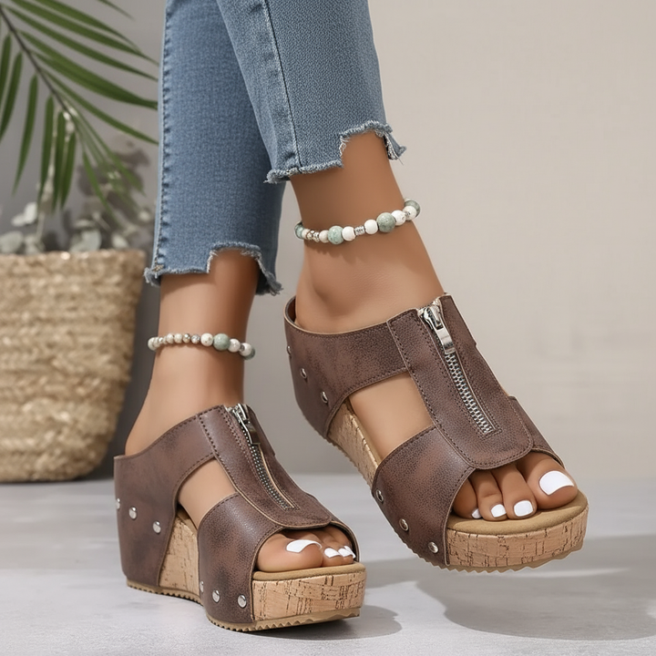 Brown wedge sandals with ankle strap, zip detail, open toe, and cork-look platform