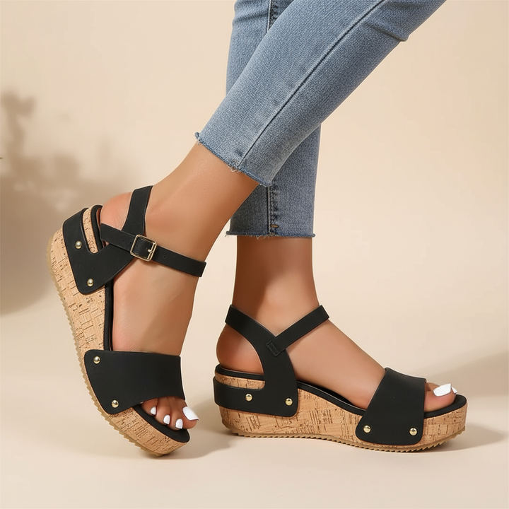 Black wedge sandals with two straps and gold-toned studs, cork-textured sole