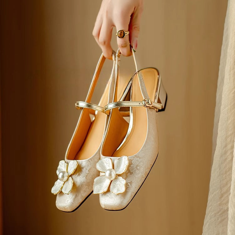 Beige elegant pumps with ankle strap, gold trim, and white flower detail