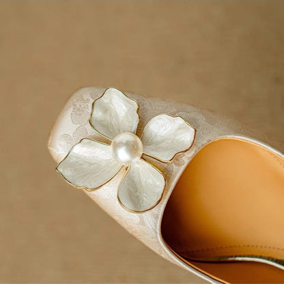 Beige pump vamp close-up with white floral appliqué and pearl center