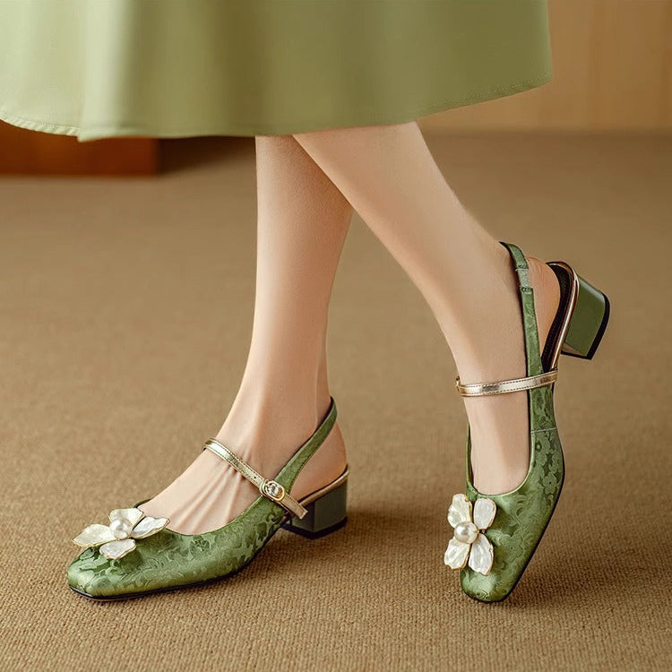 Green pumps with T-strap buckle, low block heel, and white flower ornament