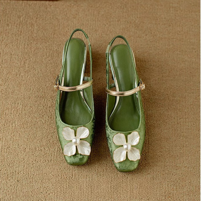 Green Mary Jane pumps with pointed toe, gold-tone strap, and white flower detail