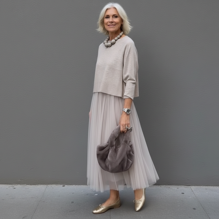 Light tan knit top with 3/4 sleeves layered over pale pleated tulle midi skirt