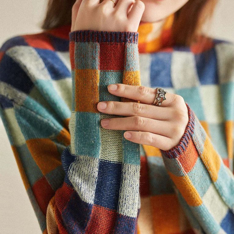 Plaid sweater sleeve cuff detail; ribbed knit with multicolor patchwork squares.
