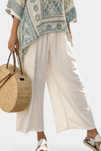 White wide-leg trousers with draped hem, styled with blue-green printed blouse