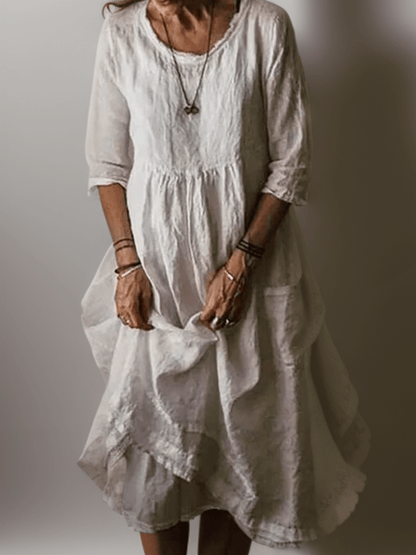 White flowing maxi dress with scoop neck, gathered waist, three-quarter sleeves and pleated tiered skirt