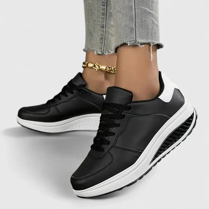 Black orthopedic sneakers, lace-up low-top with white sole and side stripe detail.