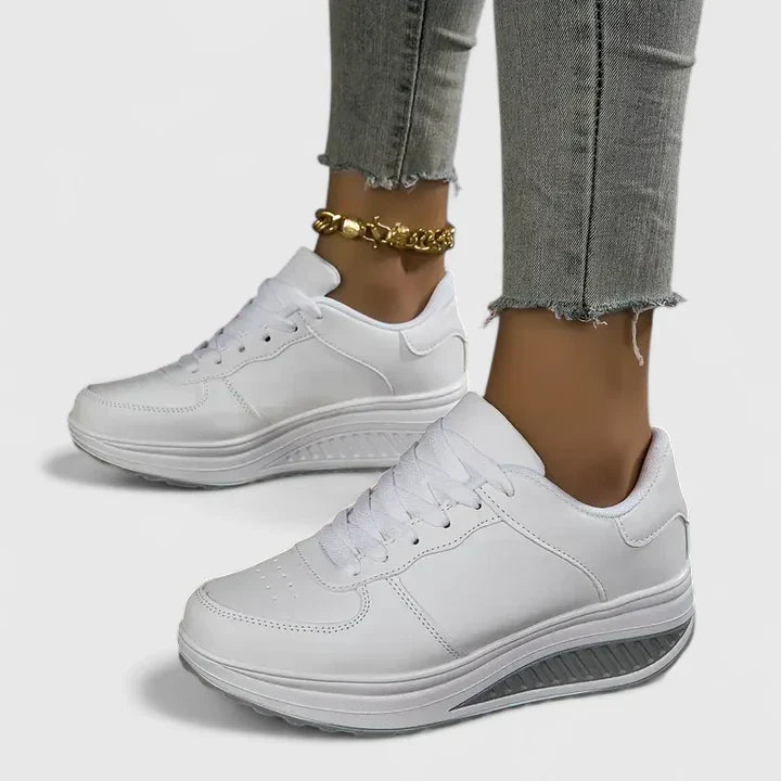 White orthopedic sneakers, lace-up low-top with cushioned collar and thick rubber sole.