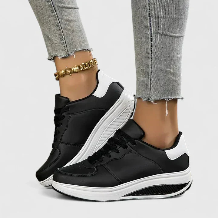 Black and white orthopedic sneakers, lace-up low-top with contrasting collar and sole.