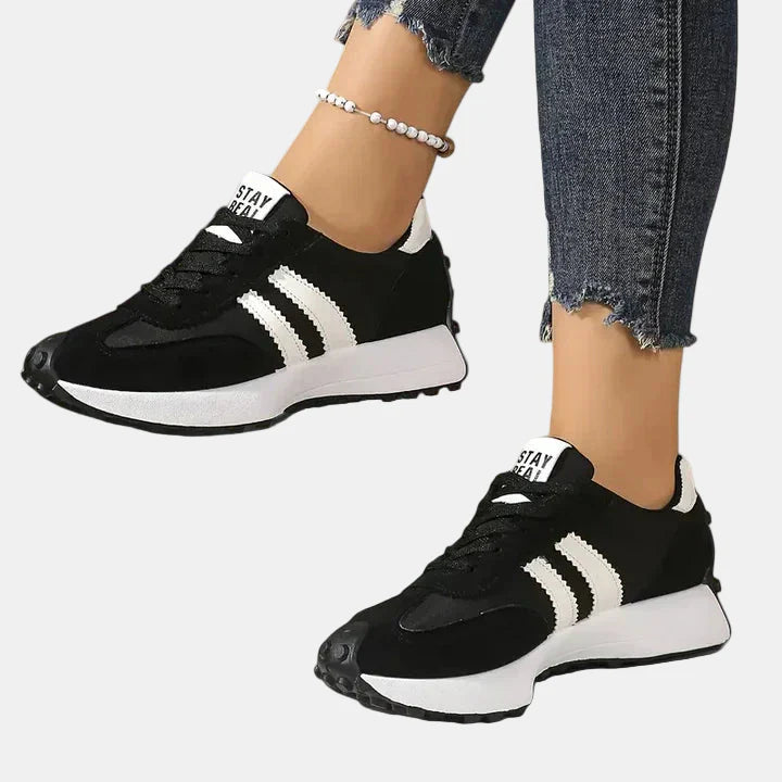 Black low-top lace-up orthopedic sneakers with white triple stripes and cushioned sole