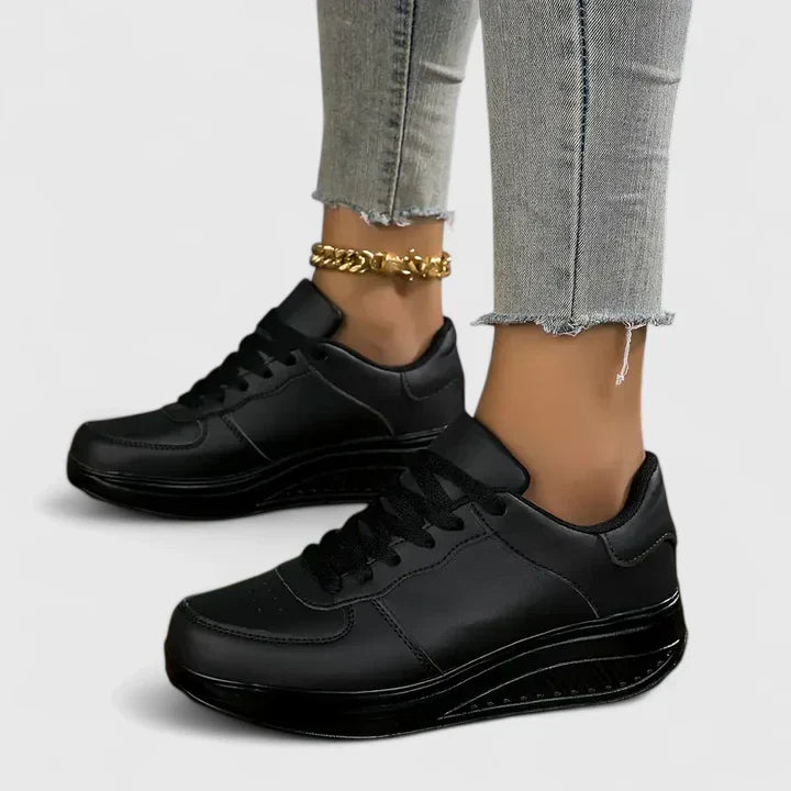 Black orthopedic sneakers, lace-up low-top with smooth upper and thick midsole.