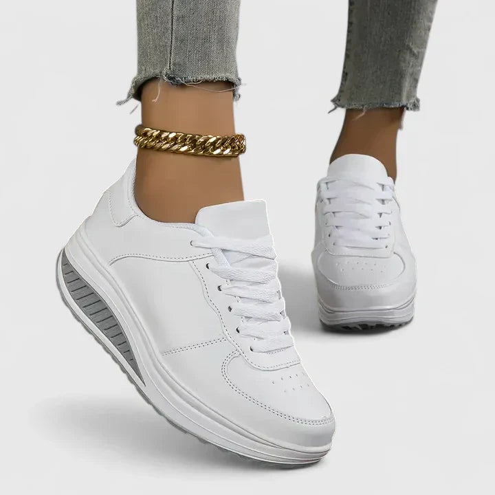 White orthopedic sneakers, lace-up low-top with padded collar and textured midsole.