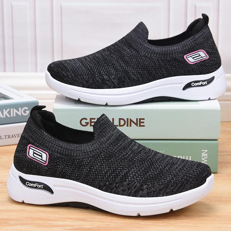 Black slip-on knit shoes with white sole and pink-bordered logo patch