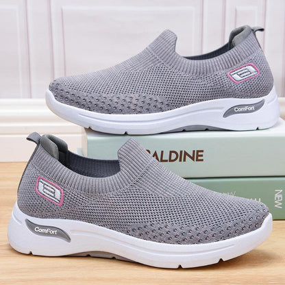 Gray slip-on knit shoes with white sole, cushioned footbed, and logo patch