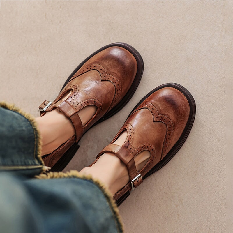 Brown leather Mary Jane flats with buckle strap and wingtip stitching, low block heel.
