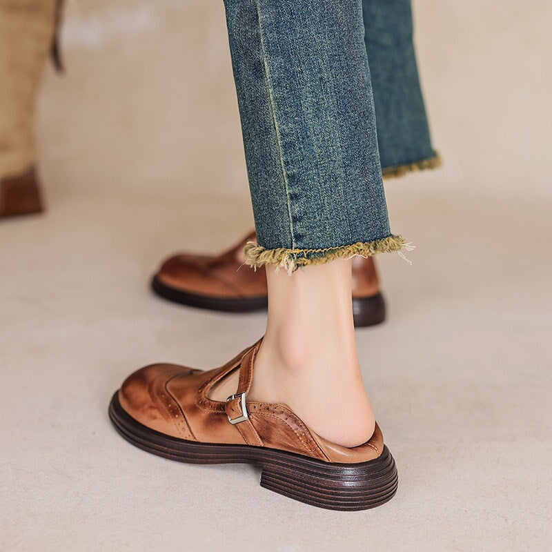 Brown leather Mary Jane shoes on feet with buckle strap and low block heel.
