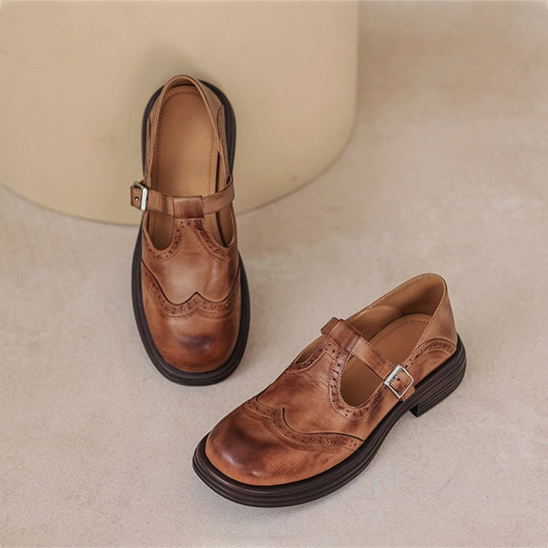 Brown leather Mary Jane shoes with buckle strap, wingtip details, low block heel.