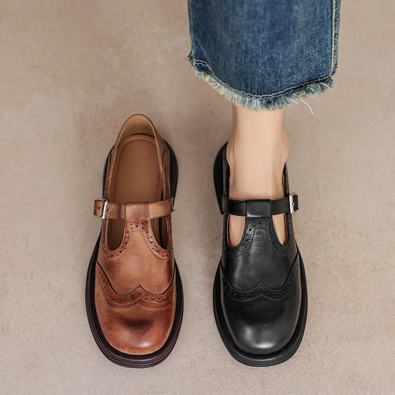 Brown and black leather Mary Jane shoes with buckle straps and wingtip stitching.