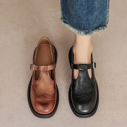 Brown and black leather Mary Jane shoes with buckle straps and wingtip stitching.
