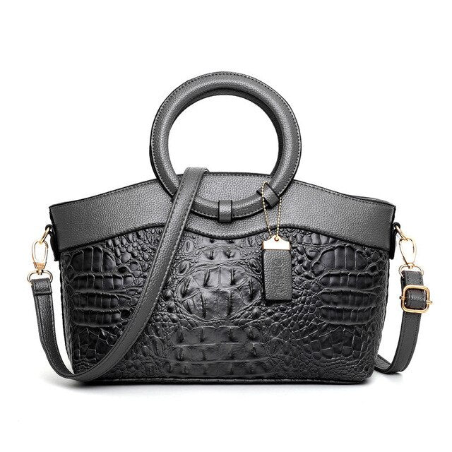 Grey croc-textured women’s handbag with top handles and crossbody strap