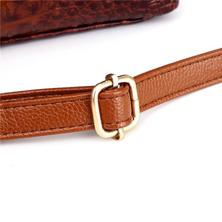 Brown handbag strap with gold-tone ring hardware and pebbled strap band close-up.