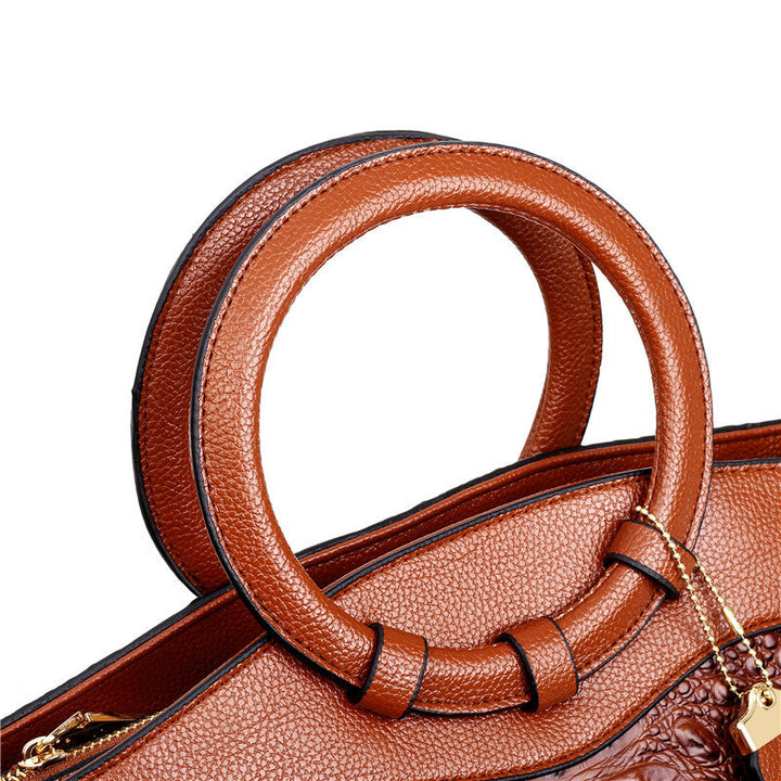 Brown croc-embossed handbag with curved top handle and matching shoulder strap.