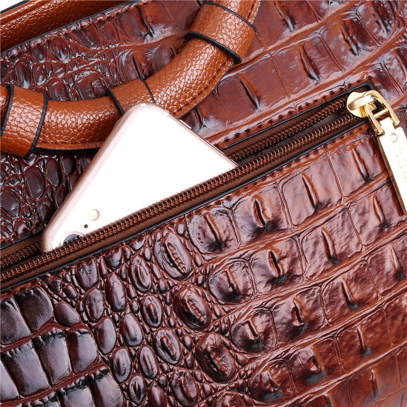 Brown croc-embossed handbag front with open zipper and gold-tone hardware.